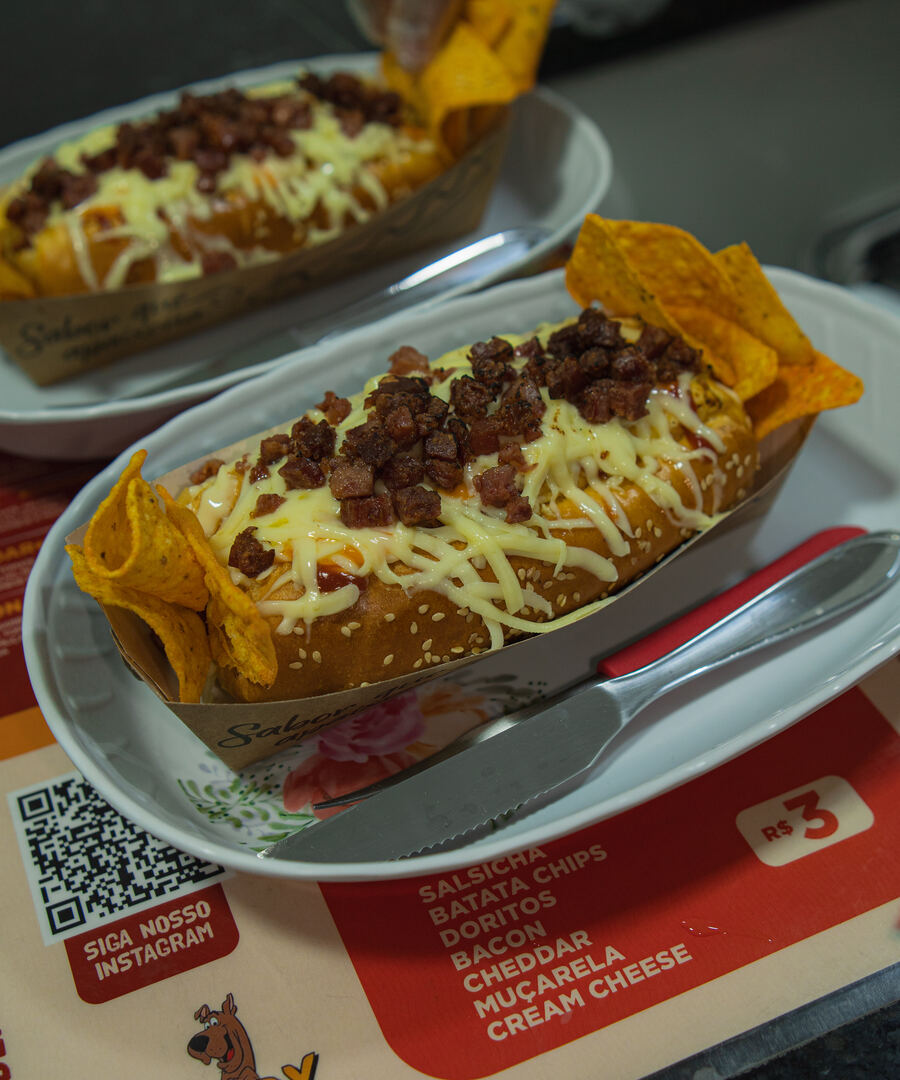Dogs da casa no capricho, com queijo derretido e farofa de bacon